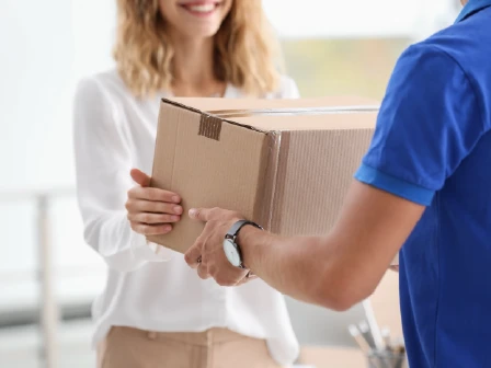 Woman accepting box from deliveryperson in blue shirt